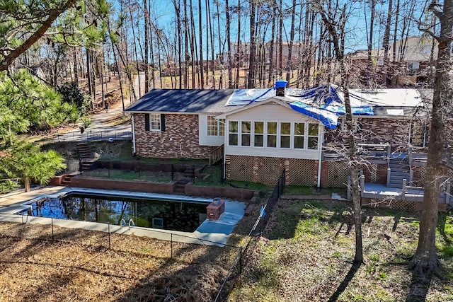 back of property with brick siding, stairway, and an outdoor pool