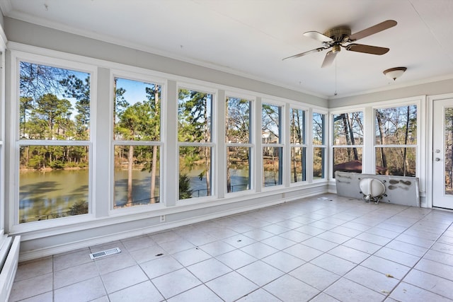 unfurnished sunroom featuring plenty of natural light, a water view, visible vents, and a ceiling fan