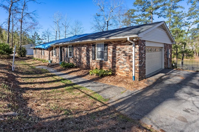 view of home's exterior with aphalt driveway, brick siding, fence, and an attached garage