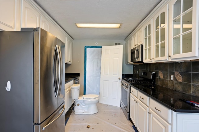 kitchen featuring stainless steel appliances, dark countertops, tasteful backsplash, visible vents, and glass insert cabinets