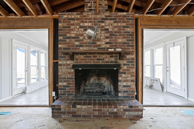 unfurnished living room featuring ornamental molding, a brick fireplace, and french doors