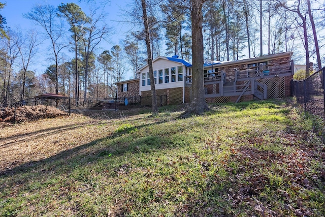 back of house featuring a deck, fence, a sunroom, stairway, and a lawn