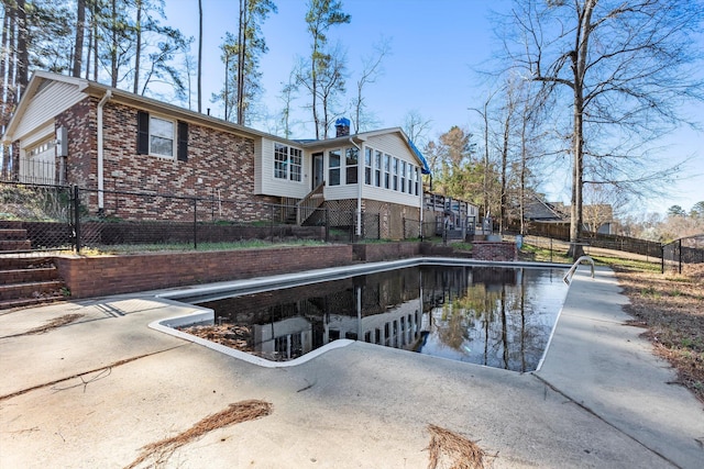 back of property with a garage, brick siding, fence, a sunroom, and stairs