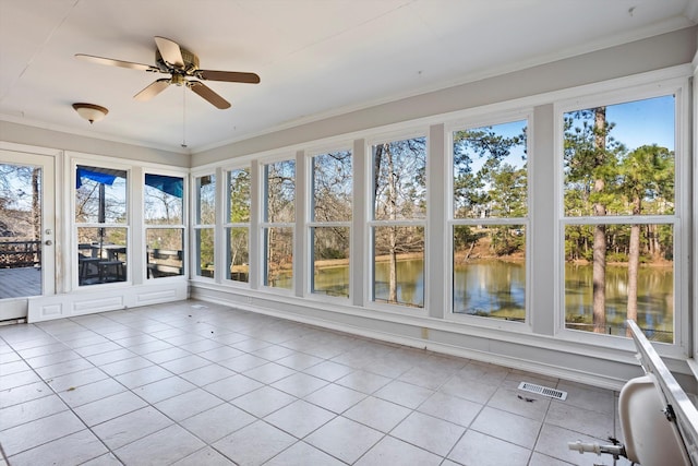 unfurnished sunroom featuring a ceiling fan, a wealth of natural light, a water view, and visible vents