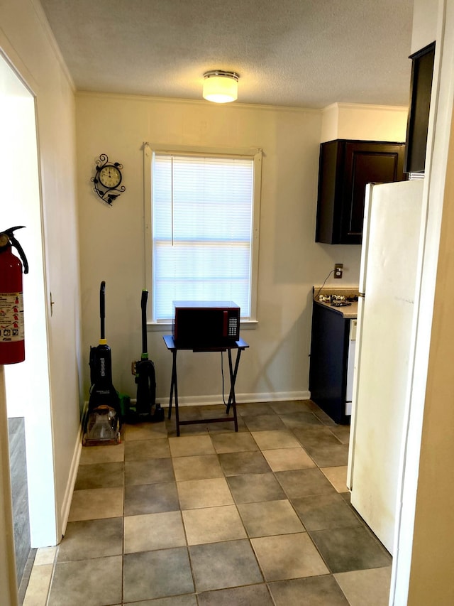 kitchen featuring dark brown cabinets, white fridge, light tile patterned floors, a textured ceiling, and crown molding