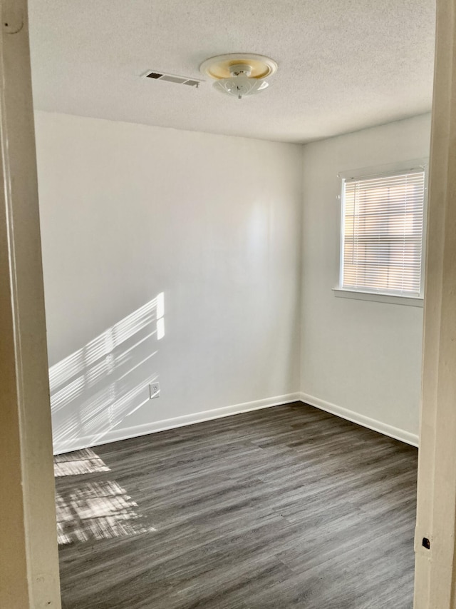 spare room featuring dark hardwood / wood-style flooring and a textured ceiling