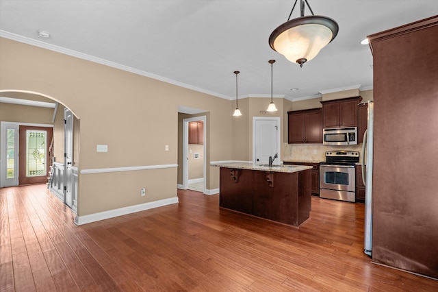 436 Sebastian Dr, Grovetown, GA 30813 - kitchen featuring appliances with stainless steel finishes, arched walkways, tasteful backsplash, dark brown cabinets, and a kitchen island with sink