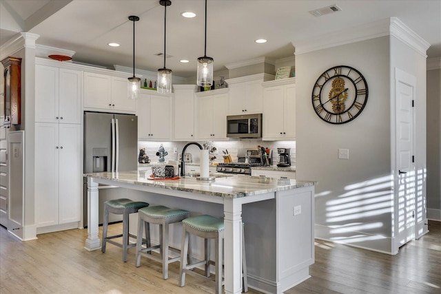 kitchen featuring white cabinets, appliances with stainless steel finishes, and ornamental molding