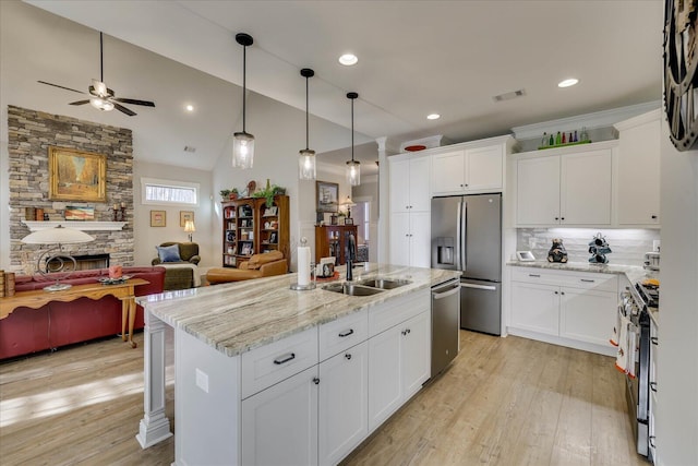 kitchen featuring visible vents, a sink, open floor plan, a stone fireplace, and appliances with stainless steel finishes