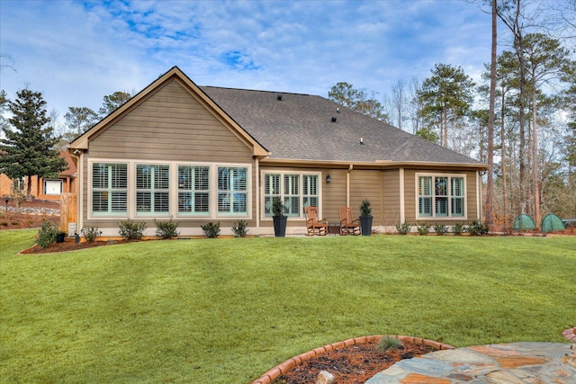 rear view of house with a shingled roof and a yard