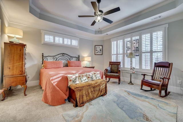 carpeted bedroom featuring visible vents, baseboards, crown molding, and a tray ceiling