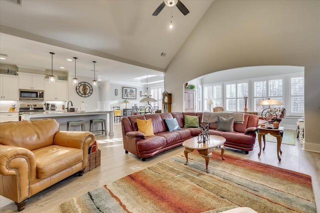 living room with ceiling fan, light wood-style flooring, a healthy amount of sunlight, and high vaulted ceiling