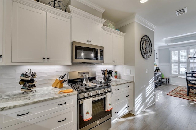 kitchen featuring tasteful backsplash, visible vents, ornamental molding, light wood-style flooring, and appliances with stainless steel finishes