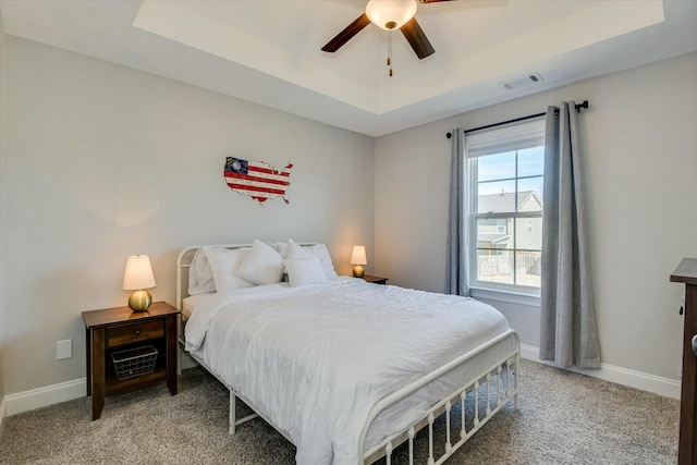 bedroom with a raised ceiling, baseboards, and visible vents