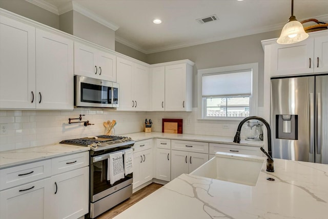 kitchen featuring visible vents, ornamental molding, a sink, white cabinetry, and stainless steel appliances