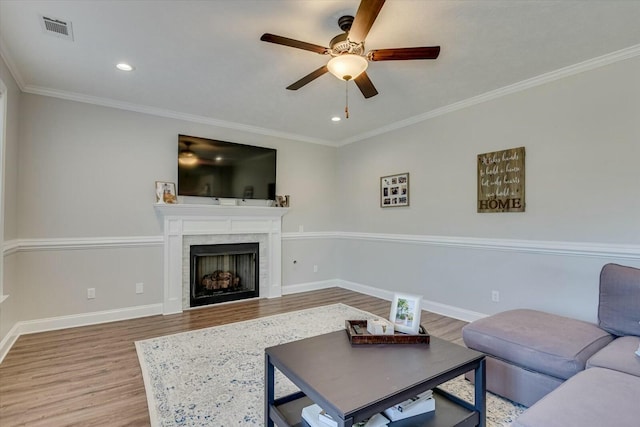 living area featuring crown molding, wood finished floors, visible vents, and baseboards