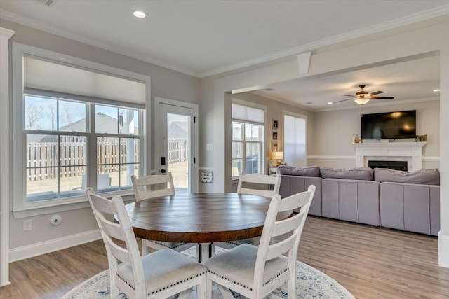 dining space with a healthy amount of sunlight, crown molding, and light wood-style floors