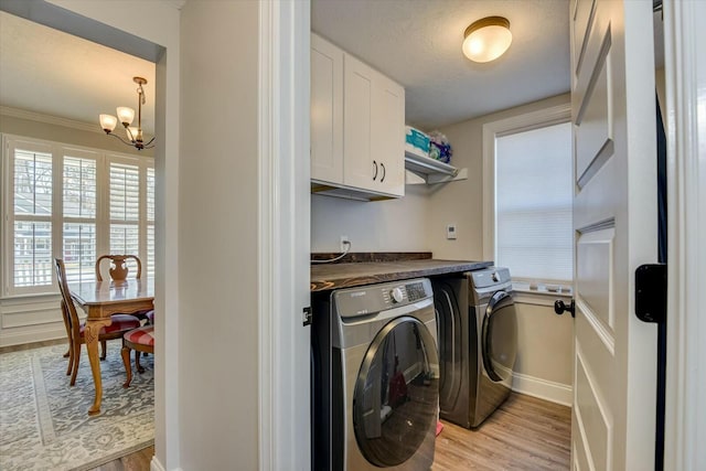 laundry room featuring washer and dryer, a textured ceiling, cabinet space, an inviting chandelier, and light wood finished floors