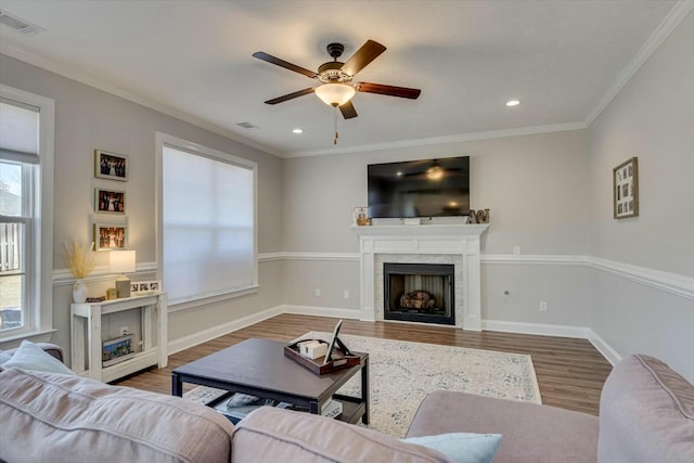 living room featuring visible vents, a tile fireplace, crown molding, and wood finished floors