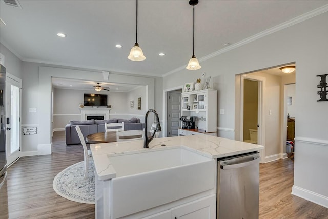 kitchen featuring open floor plan, dishwasher, ornamental molding, a fireplace, and a sink