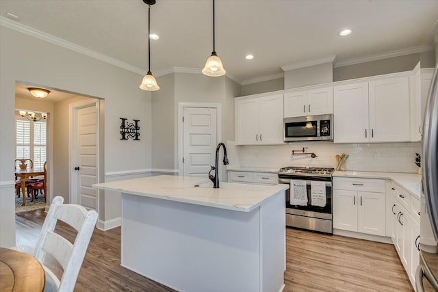 kitchen featuring light wood finished floors, appliances with stainless steel finishes, white cabinetry, and light stone counters