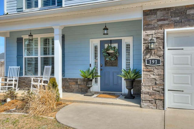 property entrance with stone siding, a porch, and an attached garage