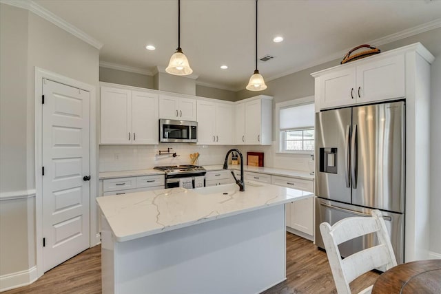 kitchen featuring wood finished floors, appliances with stainless steel finishes, white cabinetry, crown molding, and tasteful backsplash