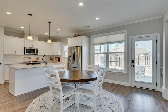 dining area featuring crown molding, recessed lighting, wood finished floors, and baseboards