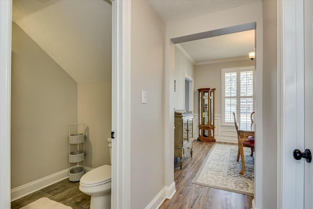 bathroom with baseboards, toilet, wood finished floors, and ornamental molding