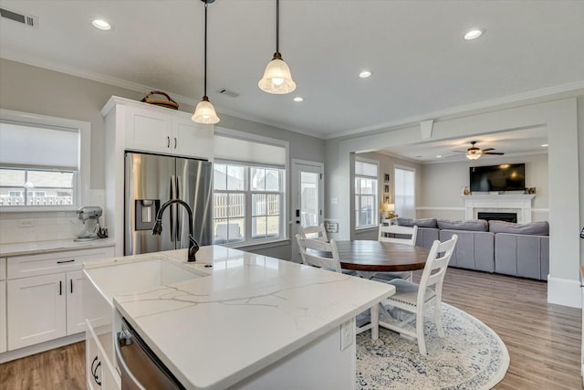 kitchen featuring light wood-type flooring, visible vents, ornamental molding, appliances with stainless steel finishes, and a fireplace