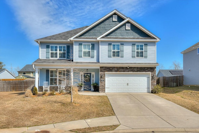 craftsman-style house with fence, a porch, a garage, stone siding, and driveway