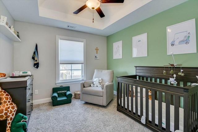 bedroom featuring visible vents, a crib, baseboards, carpet, and a raised ceiling