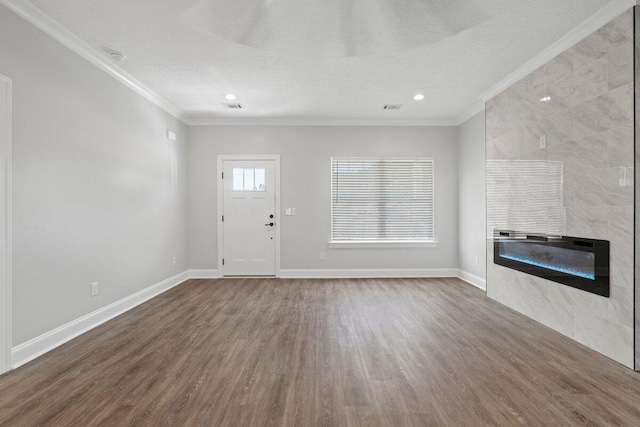 unfurnished living room featuring a textured ceiling, wood-type flooring, crown molding, and a tiled fireplace