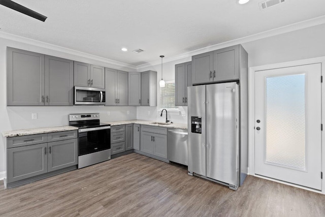 kitchen featuring gray cabinetry, hanging light fixtures, stainless steel appliances, and sink