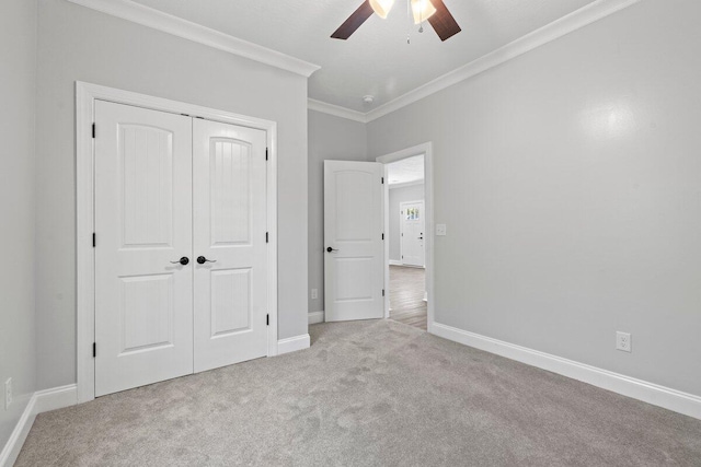 unfurnished bedroom with crown molding, ceiling fan, a closet, and light carpet