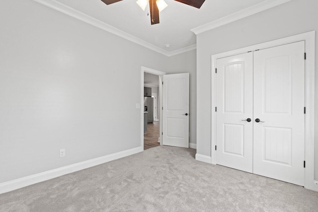 unfurnished bedroom featuring a closet, crown molding, ceiling fan, and light colored carpet