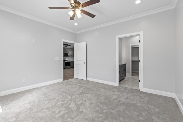 unfurnished bedroom featuring ceiling fan, light carpet, a spacious closet, and ornamental molding