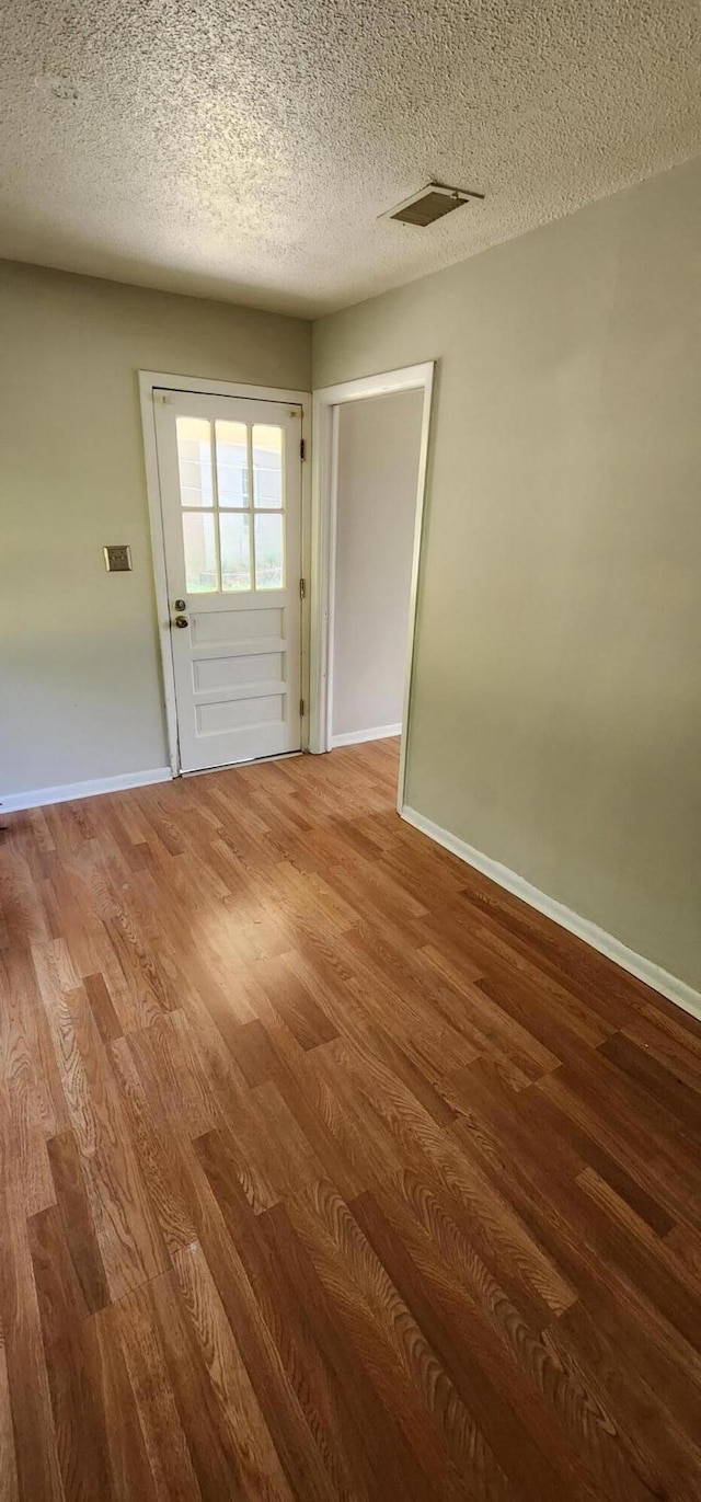 spare room featuring a textured ceiling and hardwood / wood-style flooring