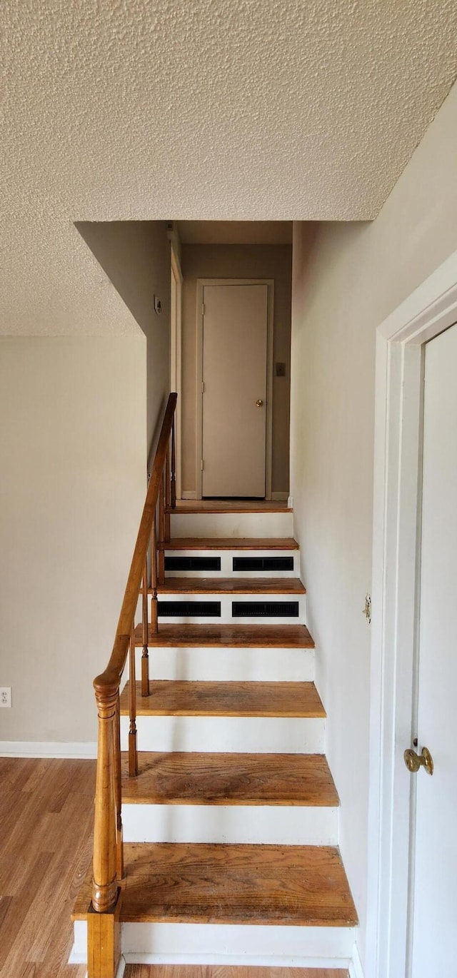 staircase featuring hardwood / wood-style floors and a textured ceiling