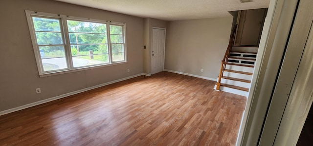 empty room with light hardwood / wood-style floors and a textured ceiling