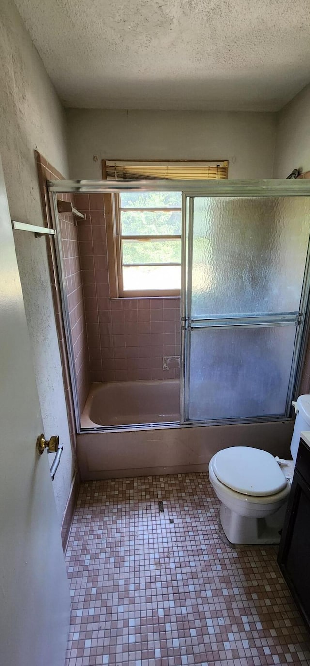 full bathroom with vanity, enclosed tub / shower combo, a textured ceiling, and toilet