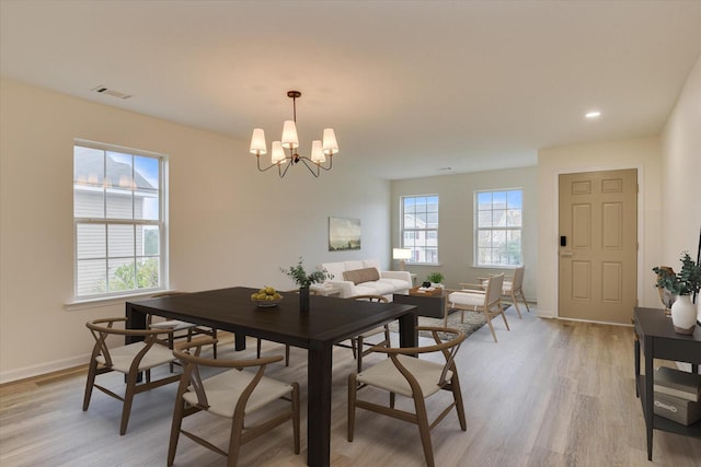 dining area with light hardwood / wood-style floors and a notable chandelier