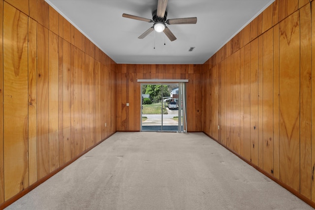 unfurnished room with ceiling fan, light colored carpet, and wooden walls