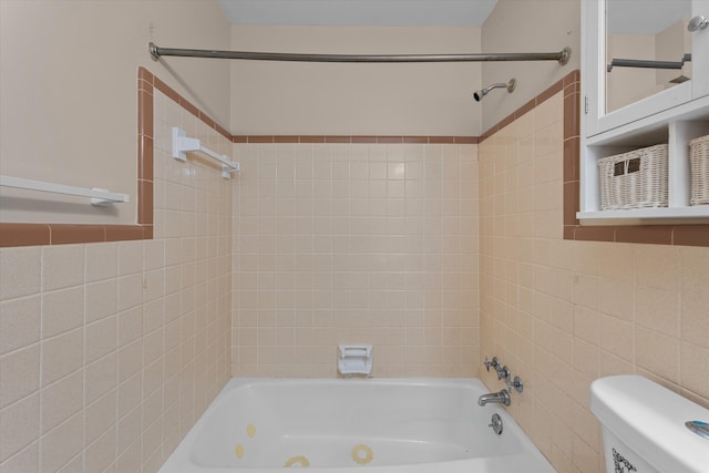 bathroom with tile walls, tiled shower / bath combo, and toilet