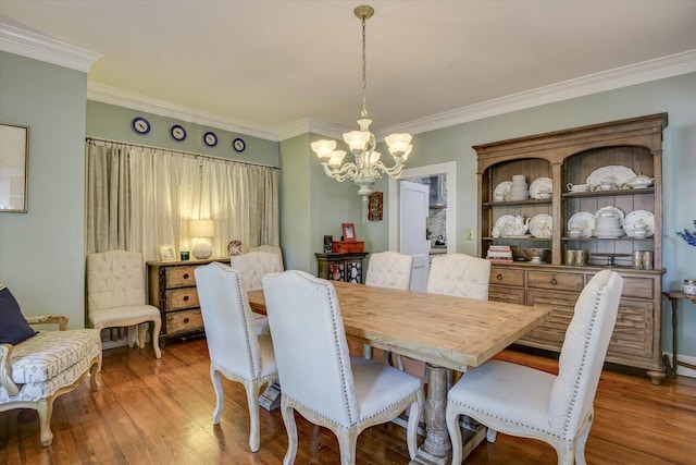 dining space featuring a notable chandelier, wood-type flooring, and ornamental molding