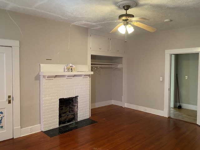 unfurnished living room featuring ceiling fan, a fireplace, dark wood-type flooring, and a textured ceiling