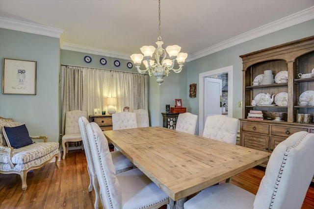 dining room with dark hardwood / wood-style flooring, an inviting chandelier, and ornamental molding