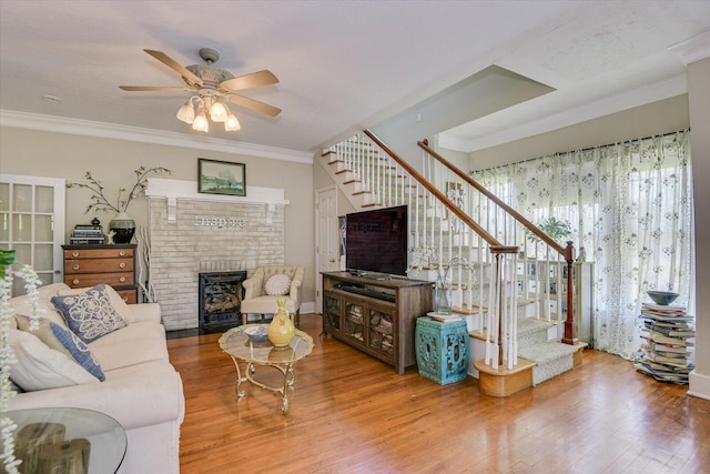 living room featuring ceiling fan, a fireplace, crown molding, and hardwood / wood-style flooring