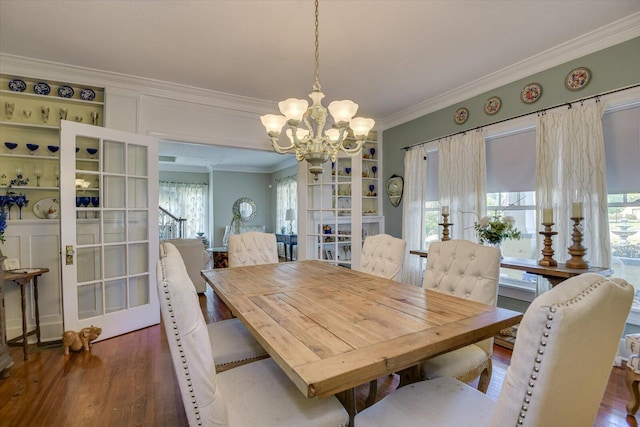 dining area featuring dark hardwood / wood-style flooring, ornamental molding, and a notable chandelier