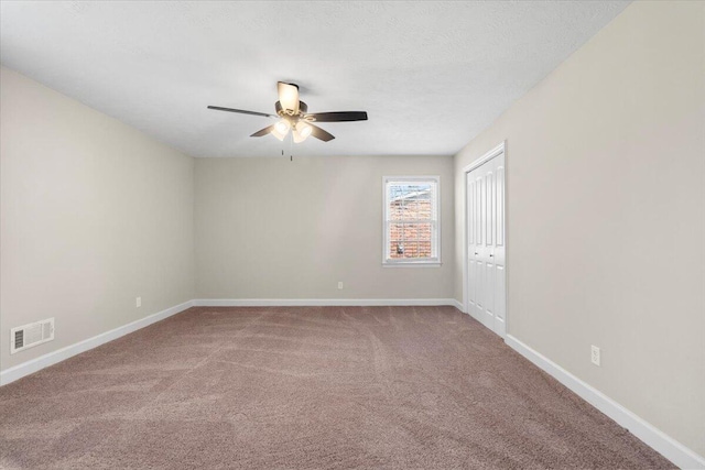 empty room featuring carpet flooring, baseboards, visible vents, and ceiling fan